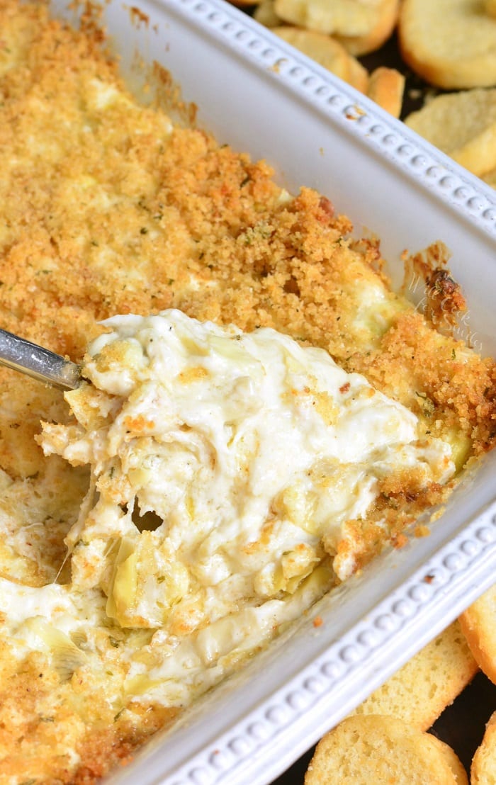 scooping out some gooey, creamy and cheesy crab and artichoke dip.
