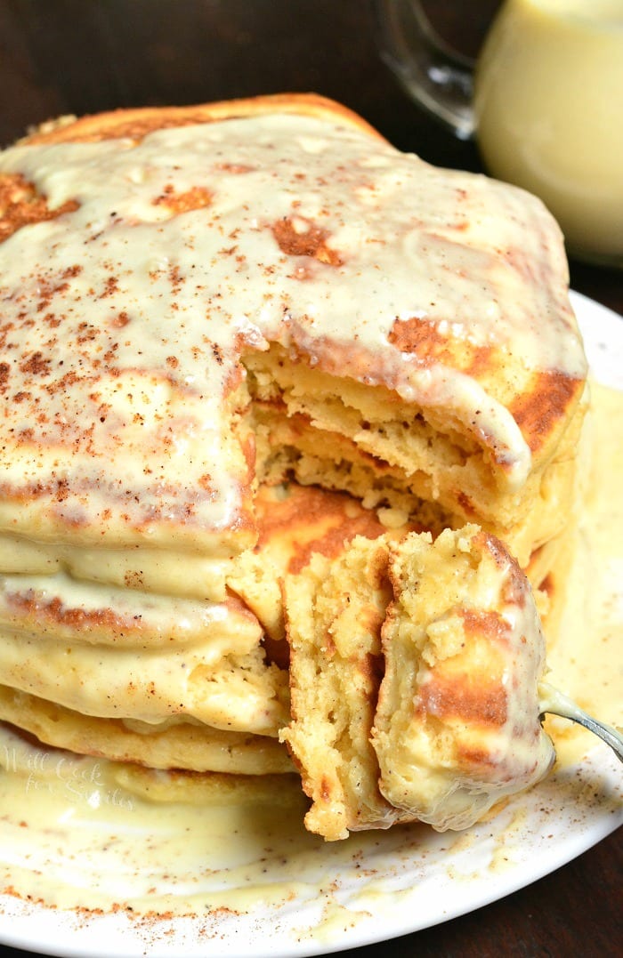 Eggnog Pancakes stacked on a plate with a bite on a fork