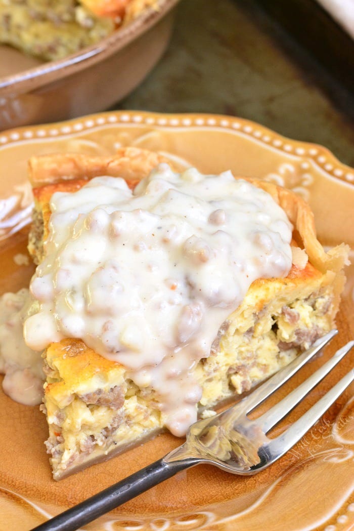 Sausage gravy quiche slice on a plate with sausage gravy over the tip.