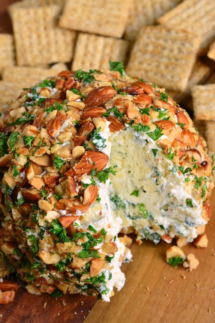 Ranch Cheddar Cheese Ball with a piece missing on a cutting board with wheat thins