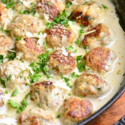 turkey meatballs in creamy sauce in a skillet with parsley garnish.