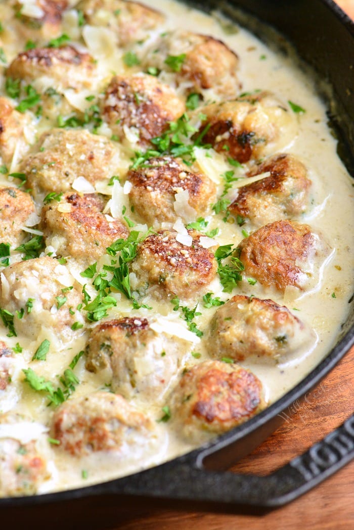 turkey meatballs in creamy sauce in a skillet with parsley garnish.