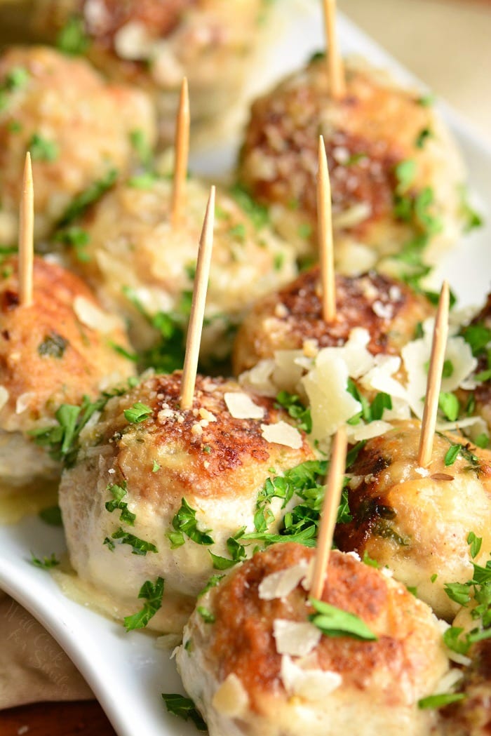 several turkey meatballs on platter with toothpicks and parmesan on top.