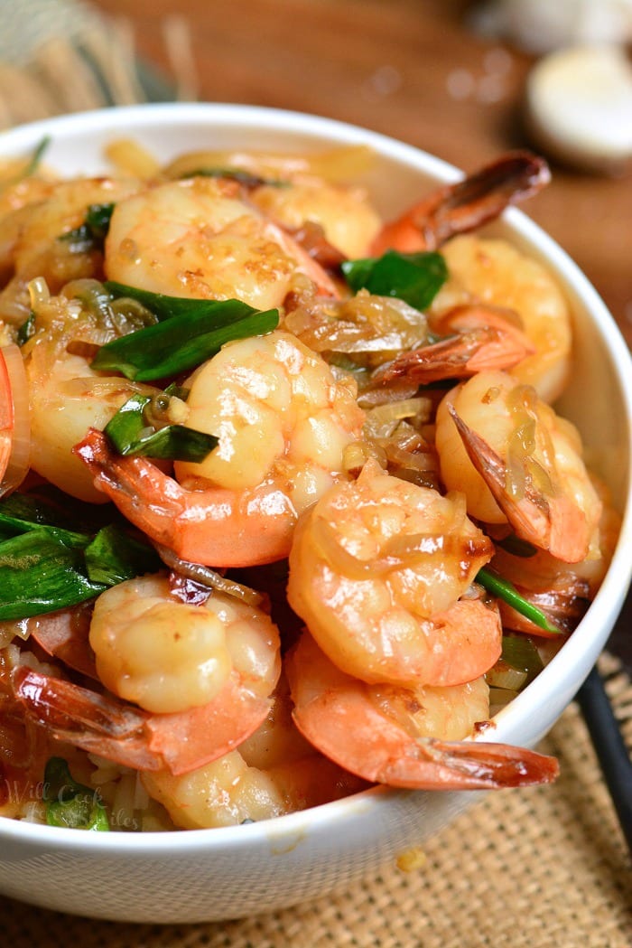 a white bowl filled with rice and topped with juicy shrimp. 