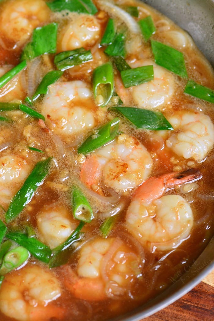 shrimp sautéing in the pan with some scallions in a garlic sauce.