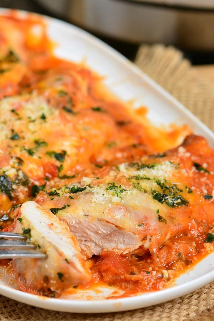 cutting out a slice from cheesy instant pot chicken parmesan breast.