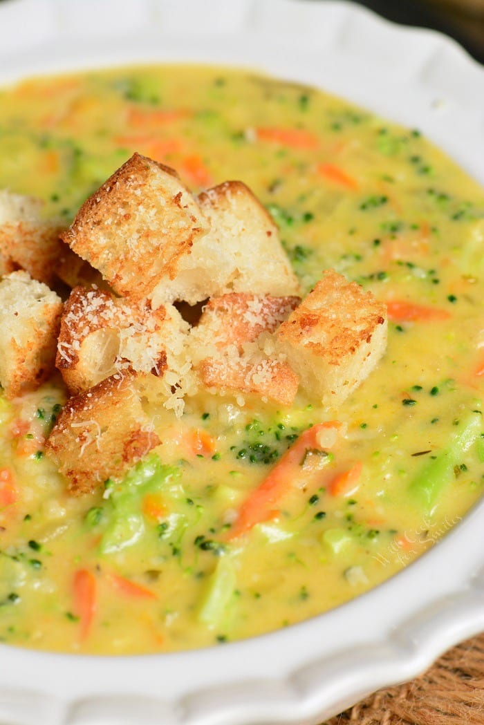 a bowl filled with creamy broccoli cheese soup topped with crispy croutons.