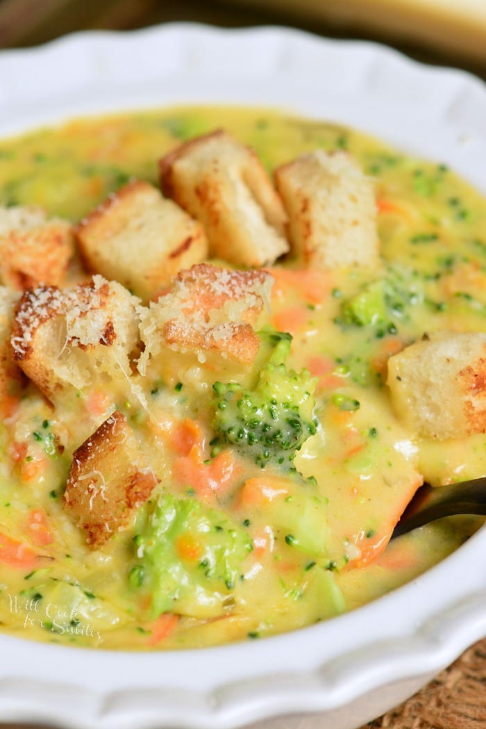starting to spoon out some broccoli cheese soup topped with croutons.