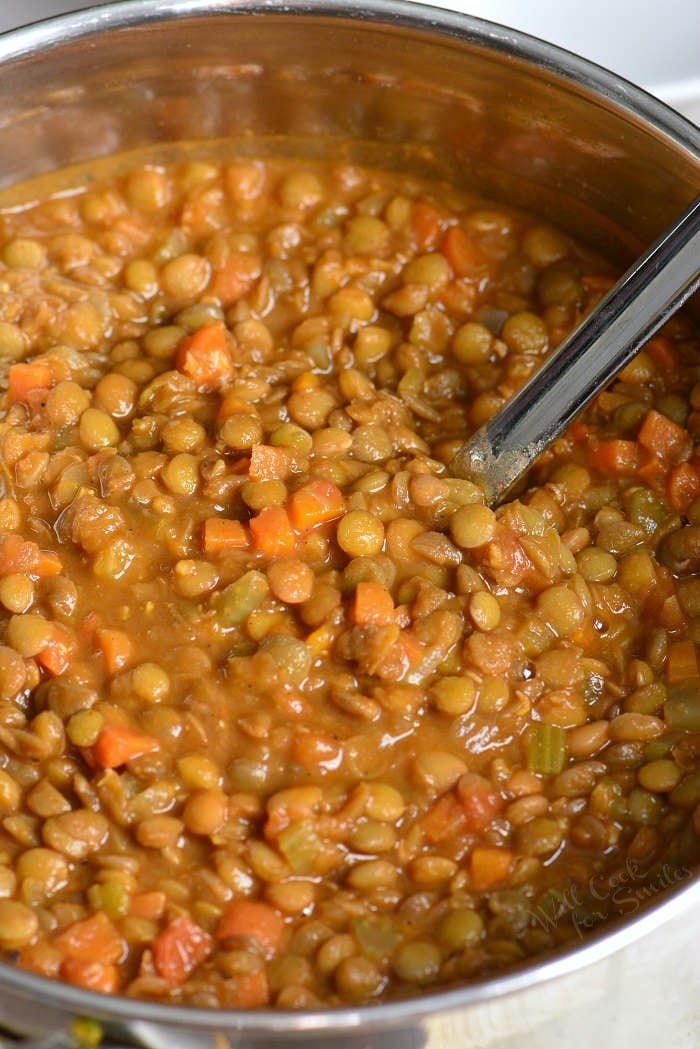 scooping out some lentil soup from a pot with a silver ladle.