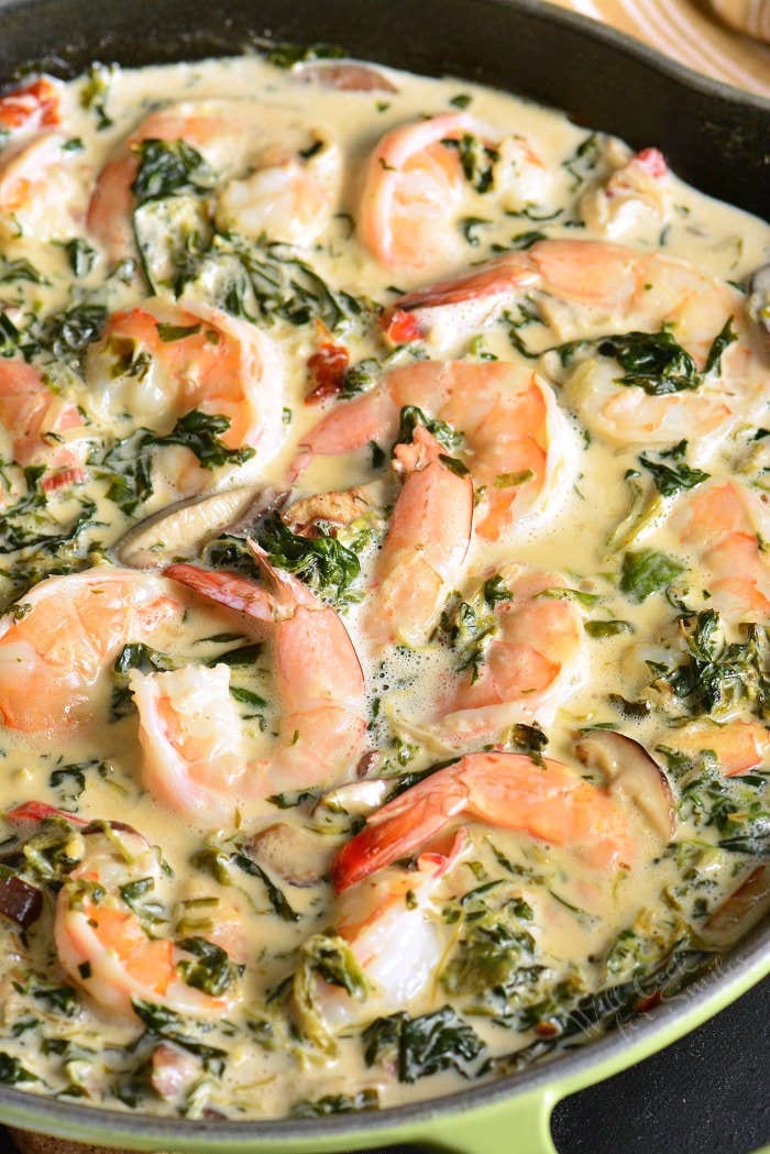 shrimp in a skillet cooked in a creamy spinach and mushroom sauce.