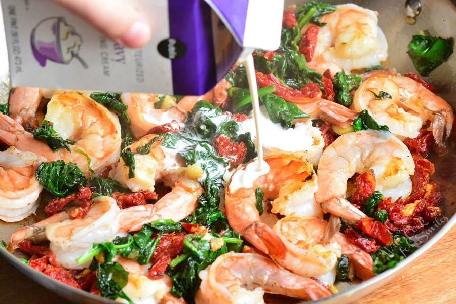 adding cream to the Tuscan shrimp ravioli cooking in the pan.