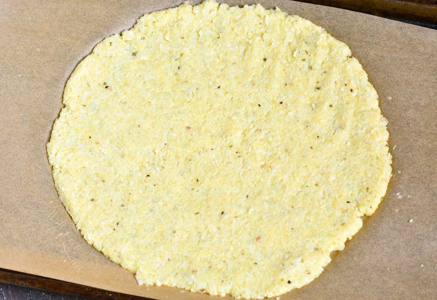 uncooked Cauliflower Pizza Crust on parchment paper