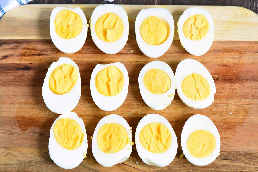 halved perfectly cooked hard boiled eggs lined on a cutting board.