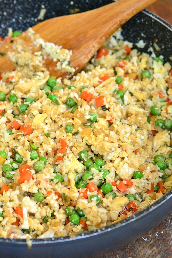 Cauliflower fried rice in a pan with a wooden spoon