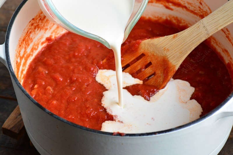 pouring cream into vodka sauce in a stock pot