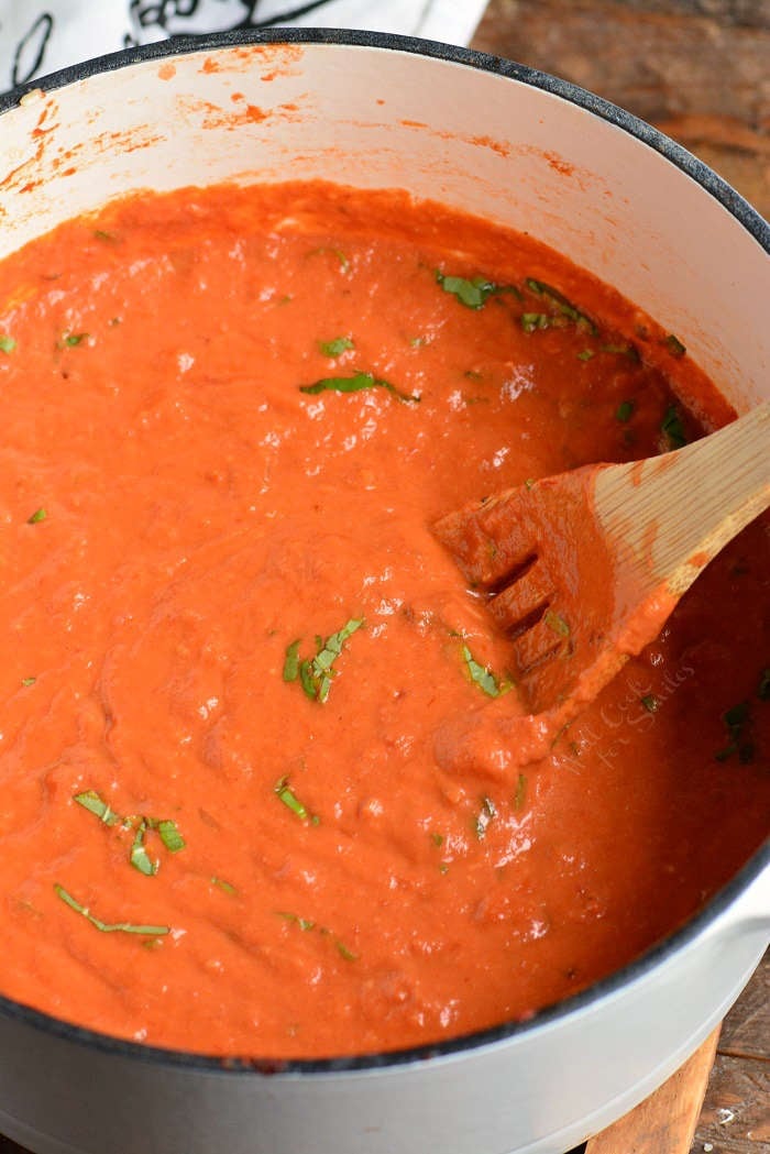 Vodka sauce recipe being stirred in a stock pot with a wooden spoon