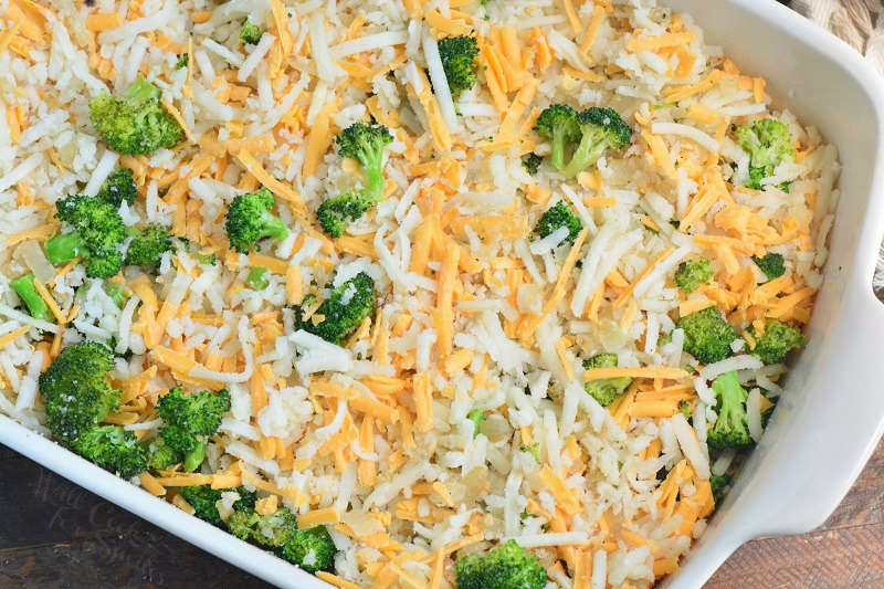 broccoli florets, hashbrowns, and cheese spread in the white baking dish.