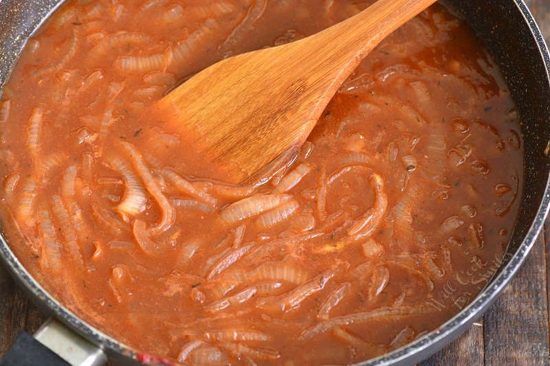 cooking the French Onion sauce in the cooking pan stirring with wooden spatula.