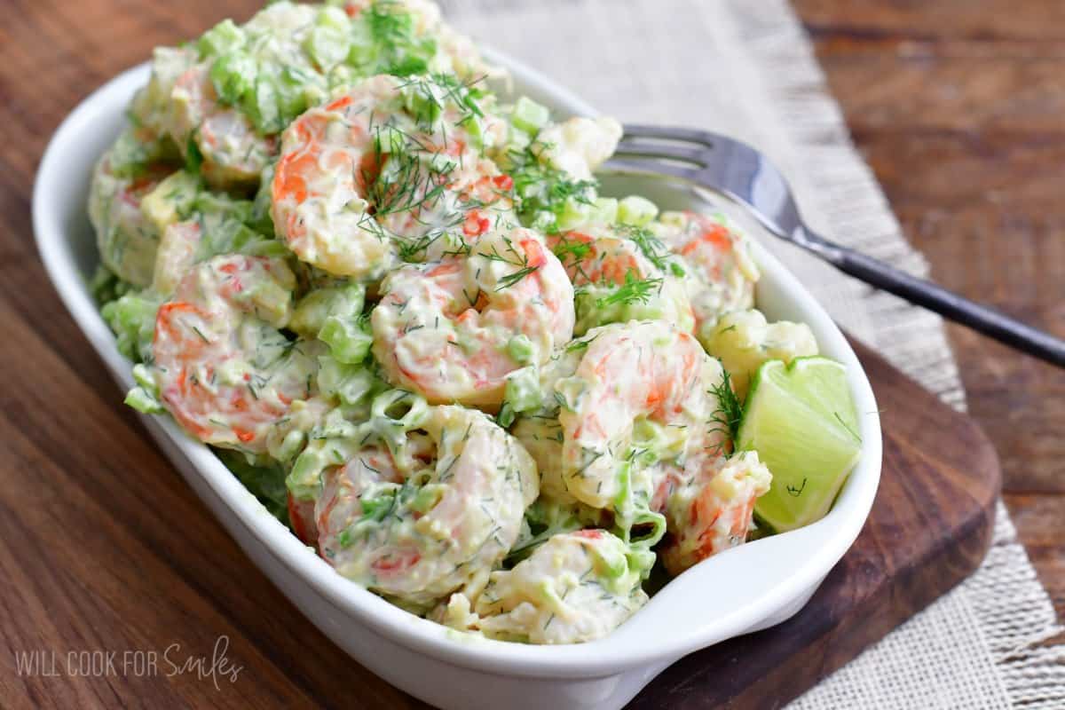 Shrimp salad in a serving dish on a wood surface.