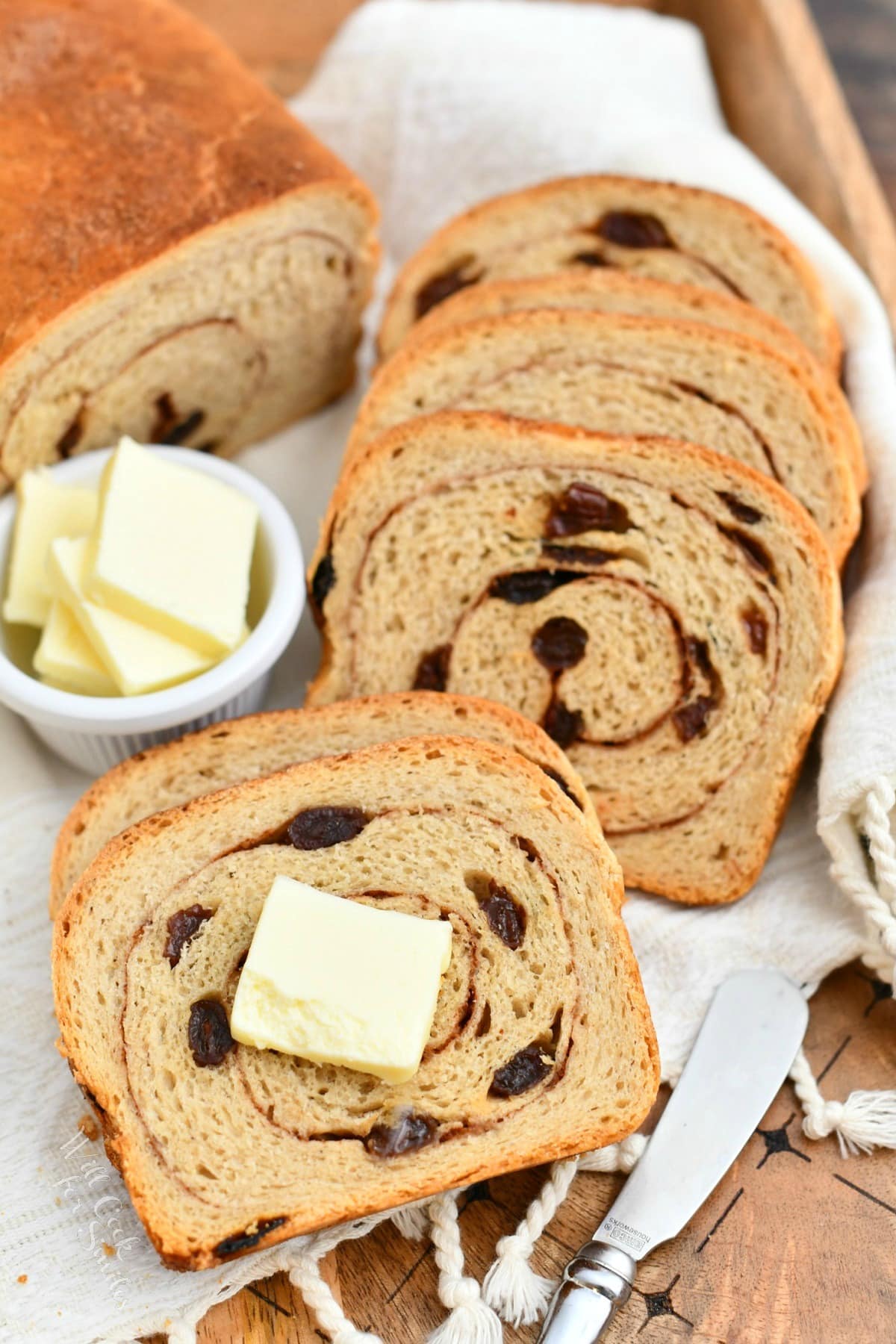 slices of freshly baked cinnamon swirl bread next to tabs of butter in white dish