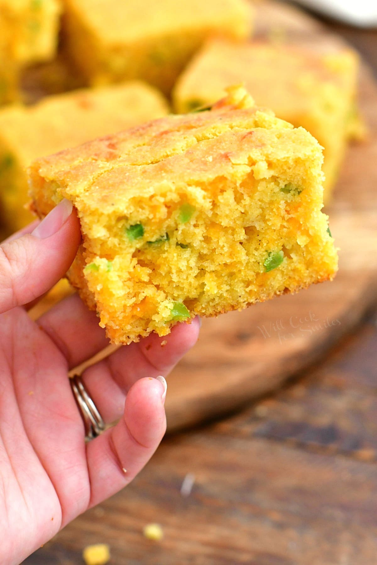 woman's hand holding a slice of jalapeno cornbread