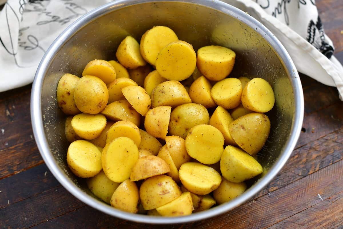 mixing bowl of raw Yukon Gold potatoes, sliced in half