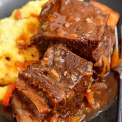 Two pieces of short rib sit on top of a helping of mashed potatoes.