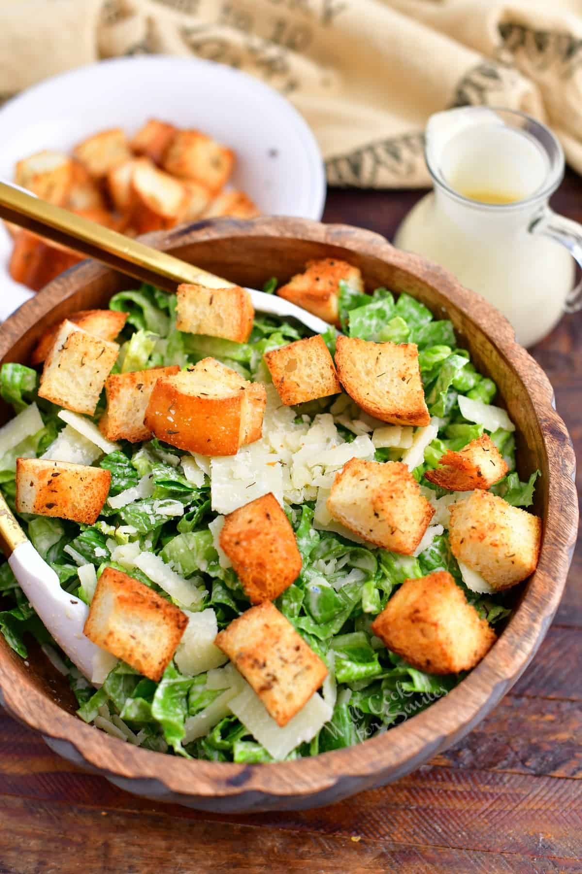 homemade caesar salad with garlic croutons and dressing in wooden bowl