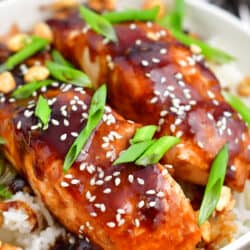 teriyaki baked salmon topped with scallions and sesame seeds on a bed of fluffy rice