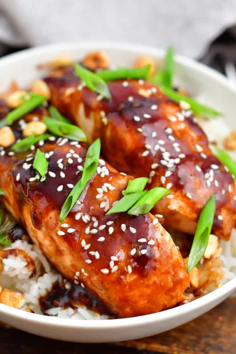 teriyaki baked salmon topped with scallions and sesame seeds on a bed of fluffy rice