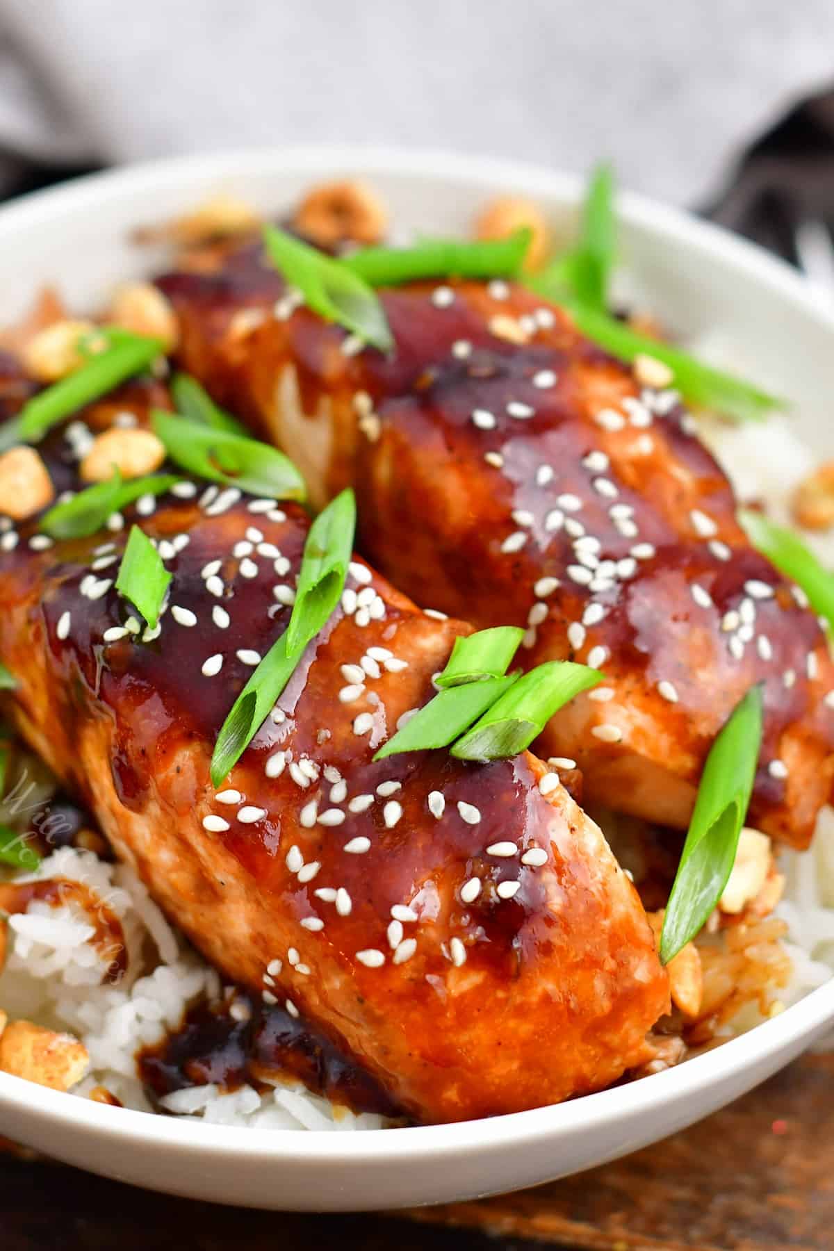teriyaki baked salmon topped with scallions and sesame seeds on a bed of fluffy rice