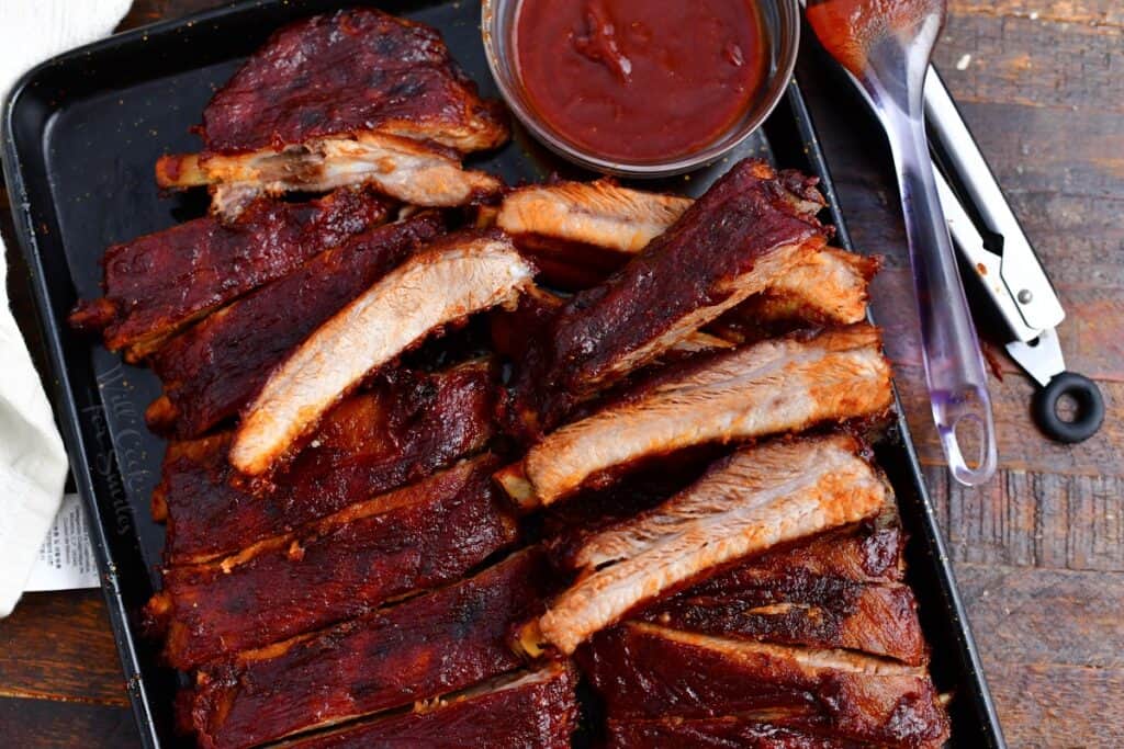 baked pork ribs on serving tray with BBQ sauce