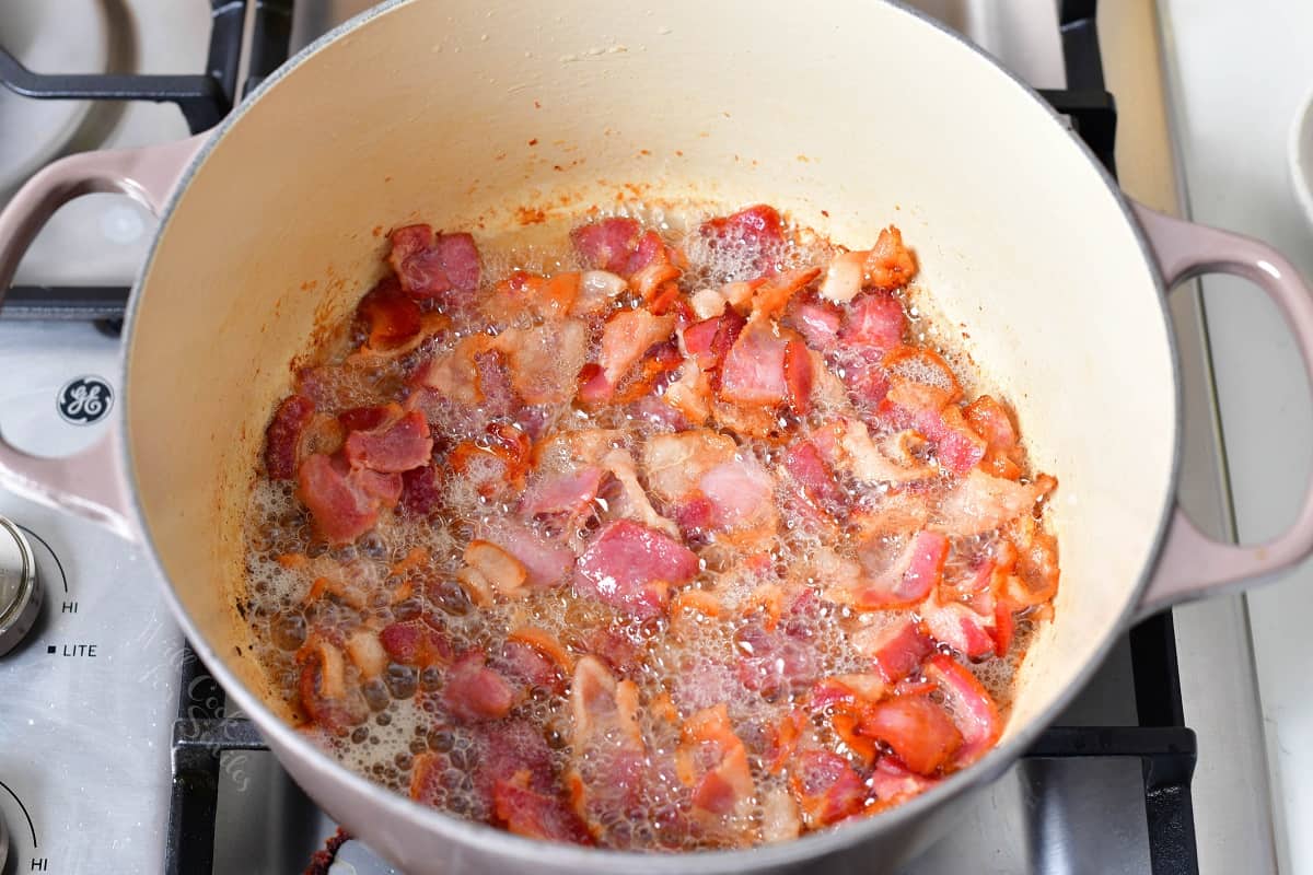 Bacon is being cooked at the bottom of a pot.