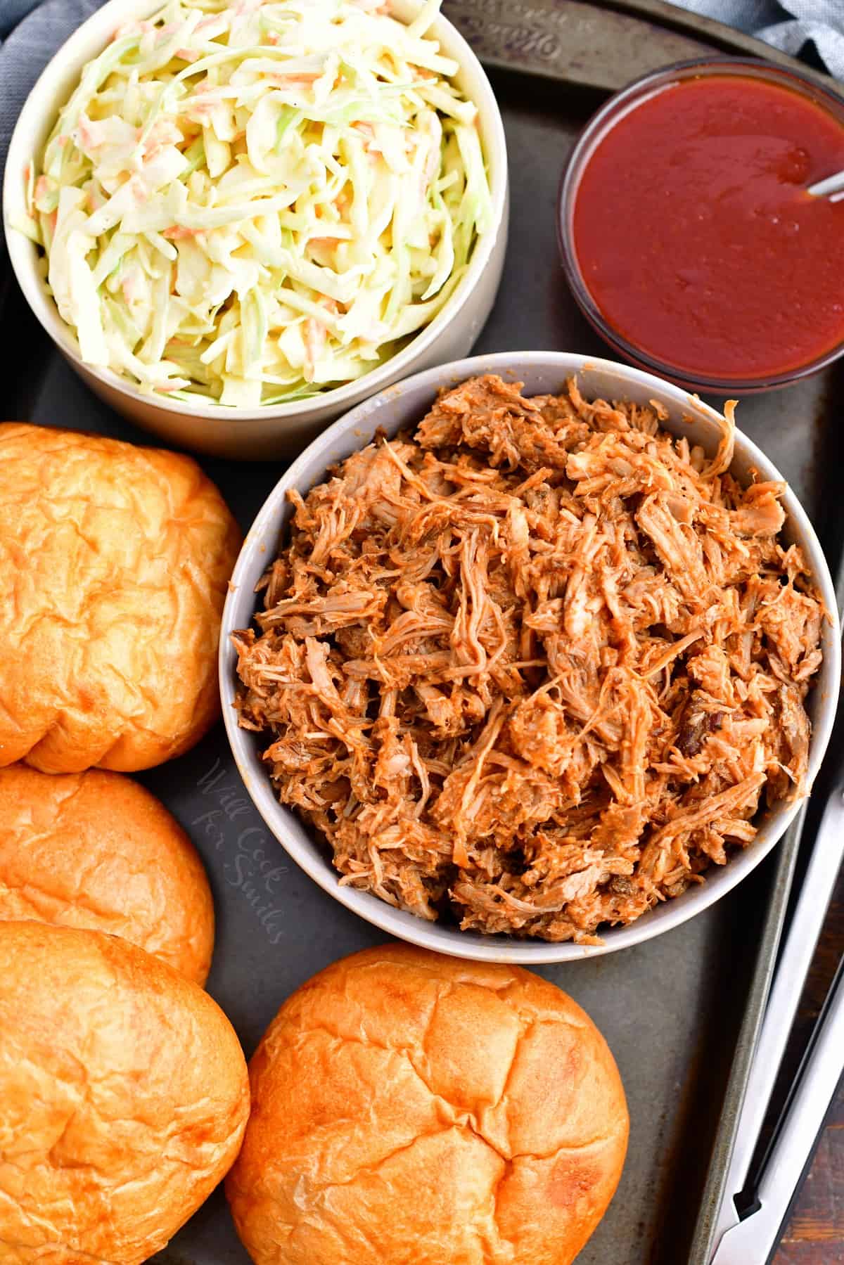 The ingredients for pulled pork sandwiches are presented on a metal surface.