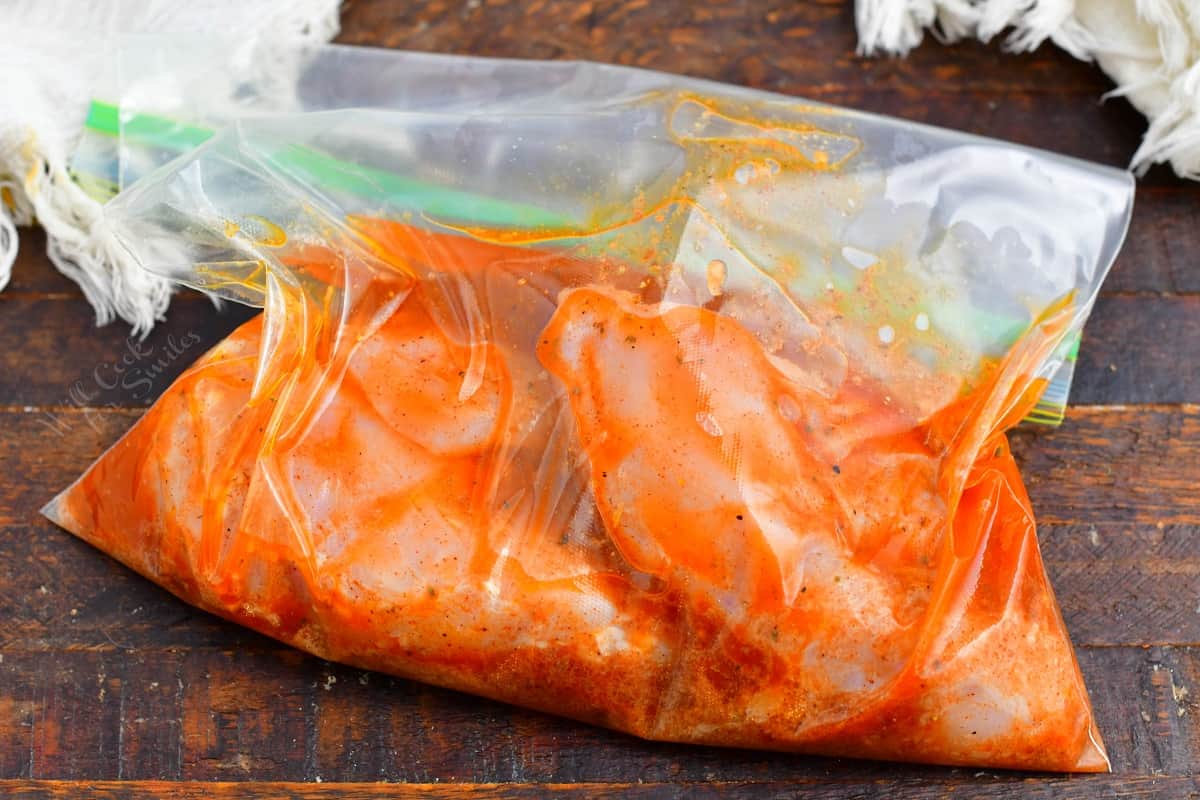 Chicken is marinating in a plastic bag.