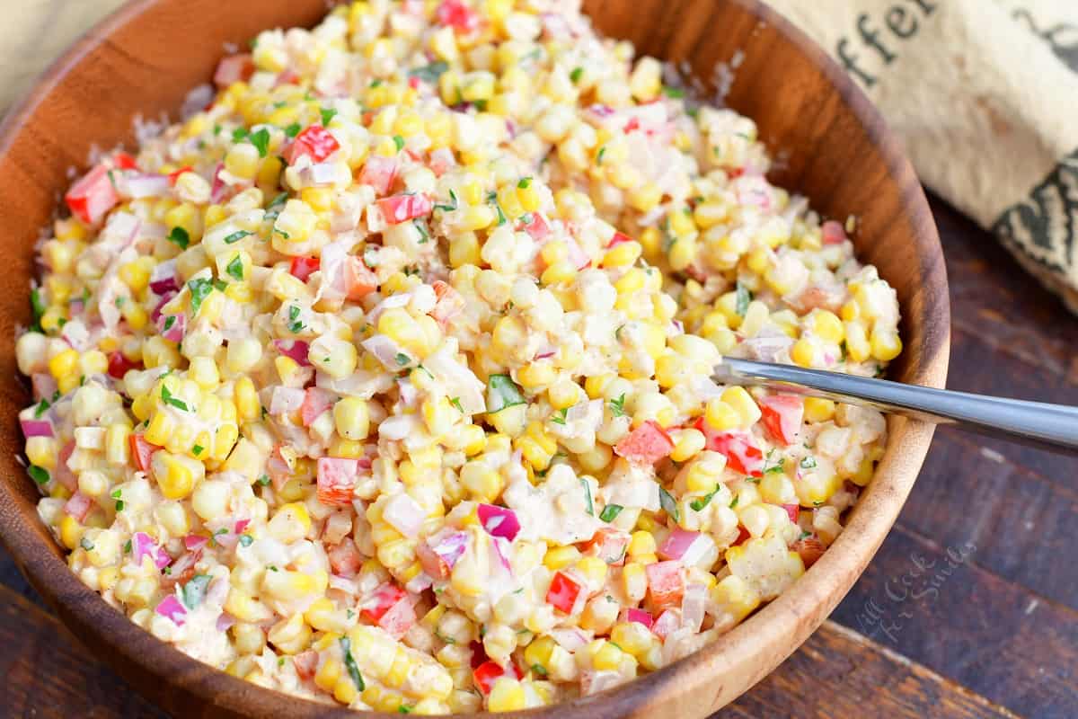 A serving spoon has been placed in the creamy corn salad.