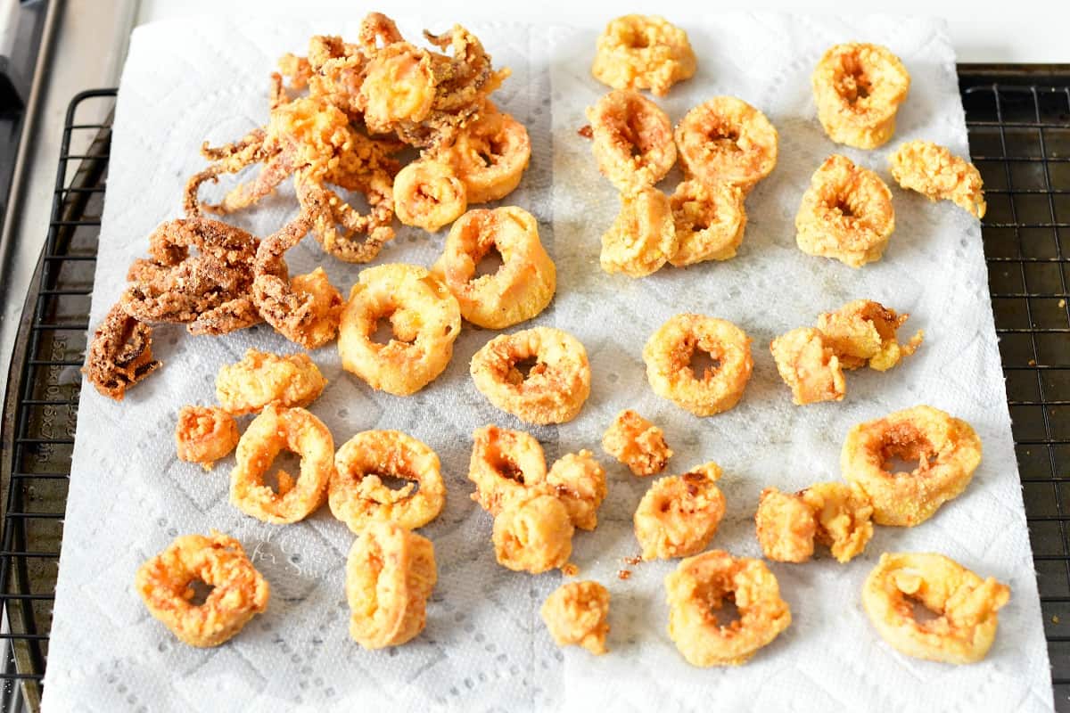 Fried calamari pieces are placed on a sheet of paper towels.