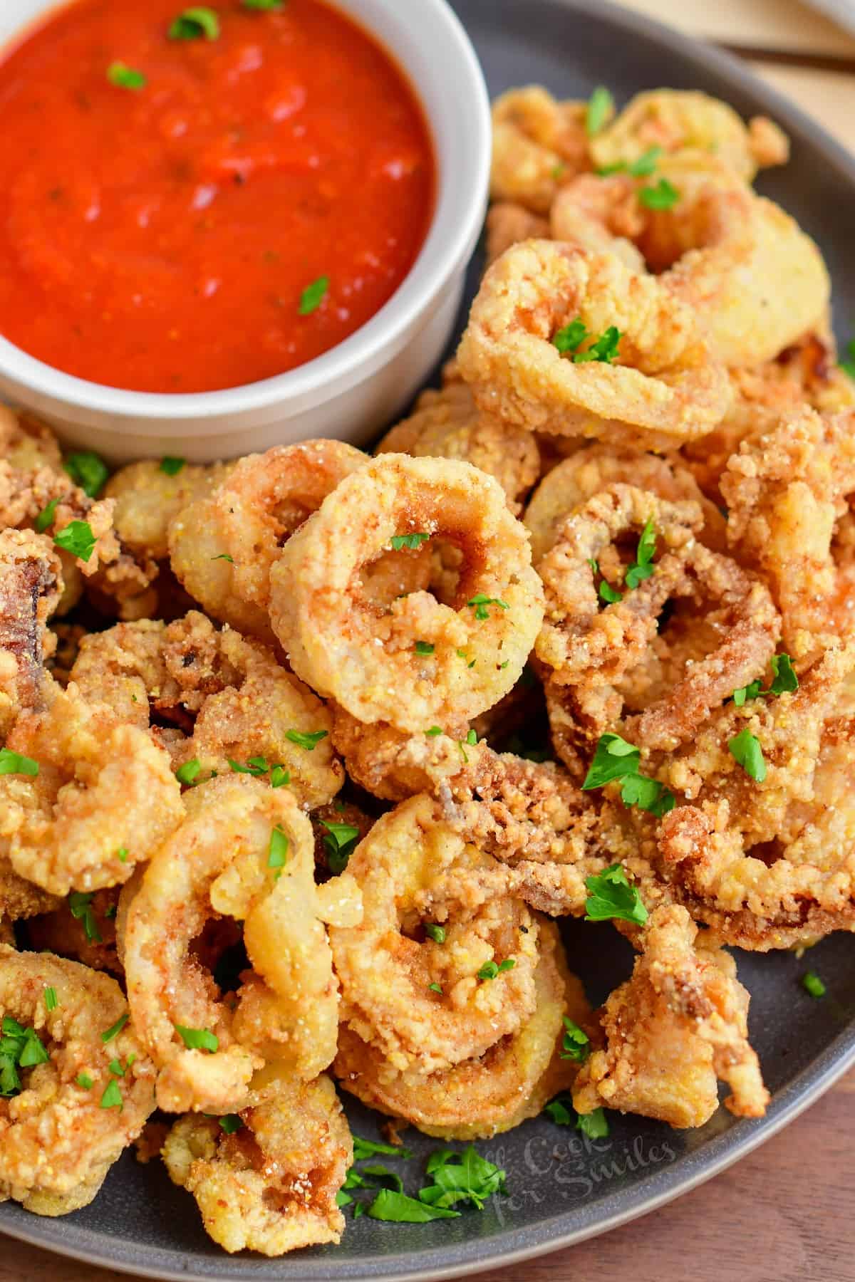 Calamari is fried, plated, and garnished with fresh parsley.