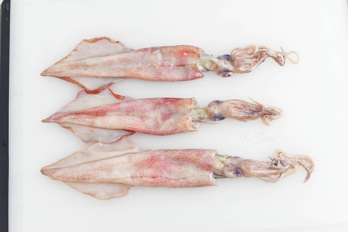 three whole squid on a cutting board