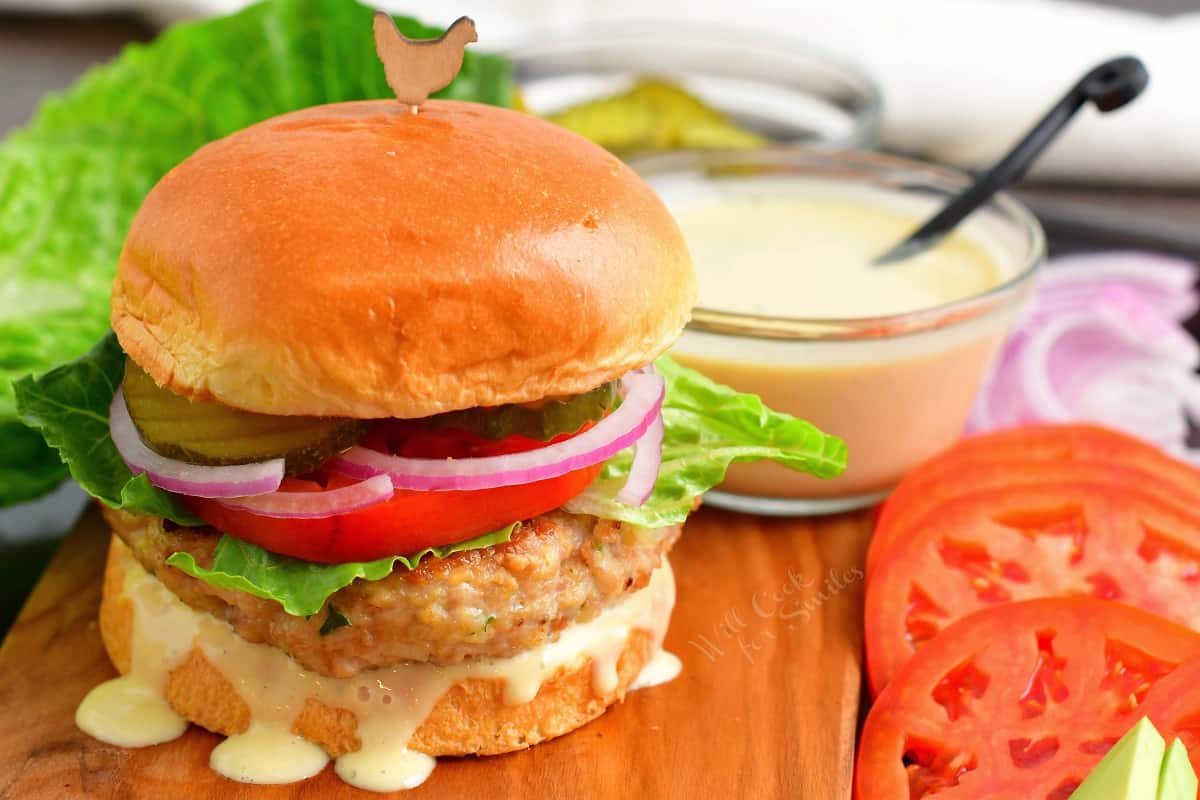 chicken burger on Brioche bun with vegetable topping and creamy sauce.
