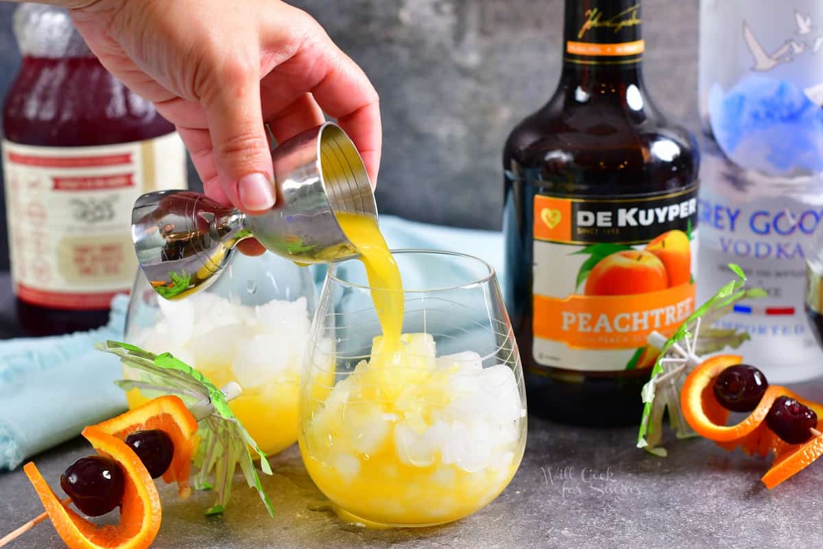 Peach schnapps is being poured into a glass with ice.