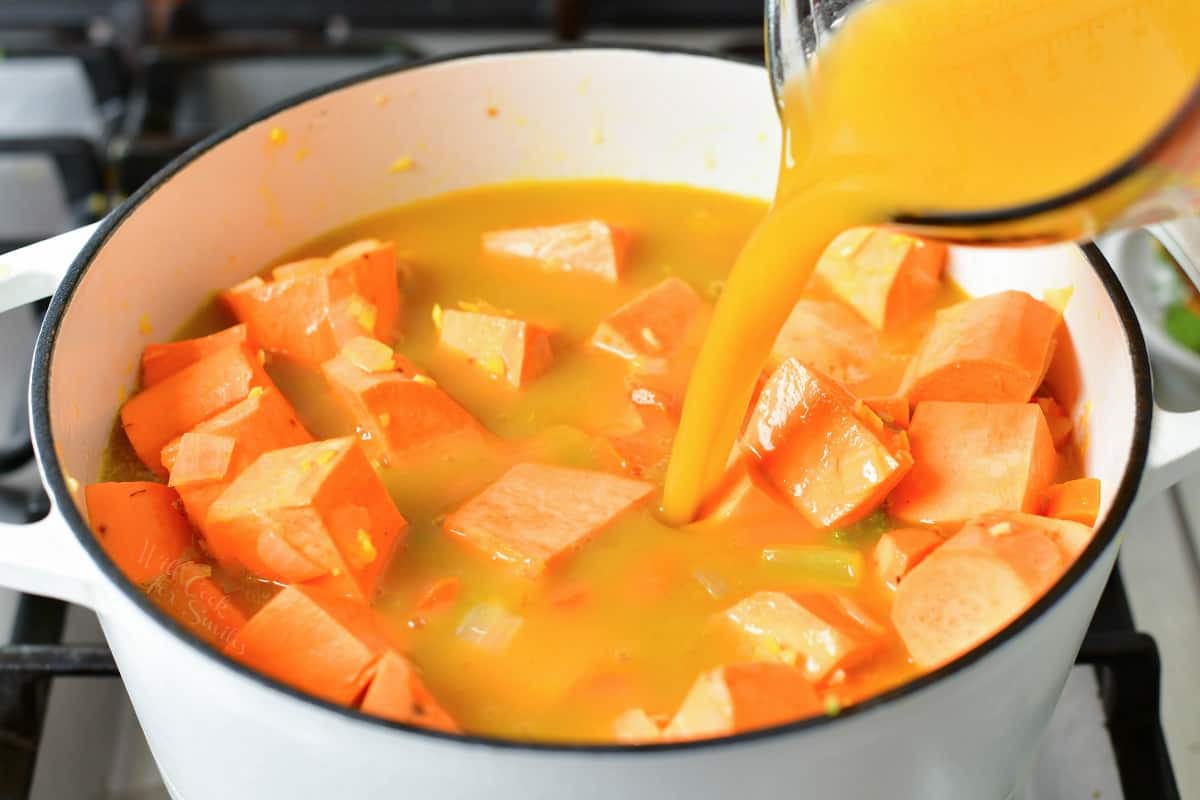 adding vegetable broth to the pot of sweet potatoes.