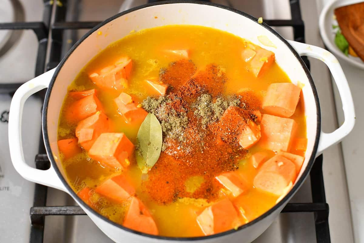 sweet potatoes covered in broth and topped with seasoning in a pot.