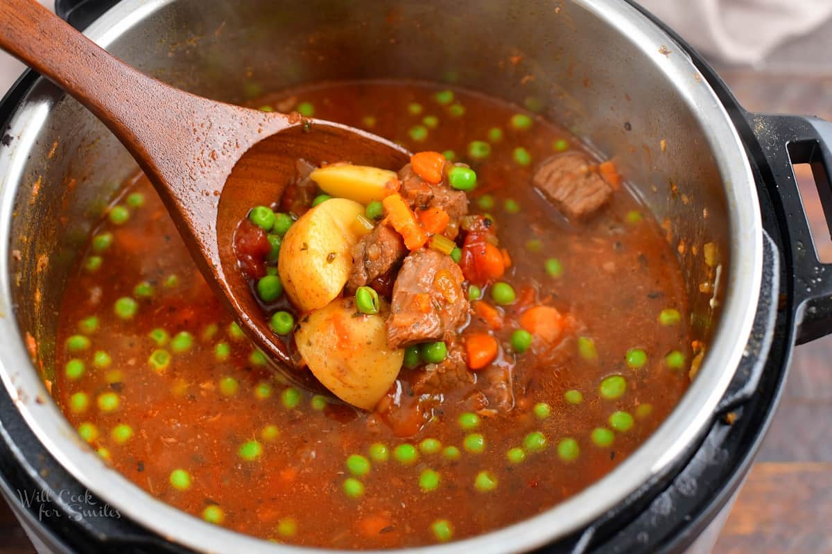 Scooping some soup out of the pot with a wooden ladle