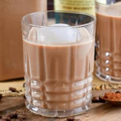 closeup of a highball glass with creamy brown cocktail and ice.