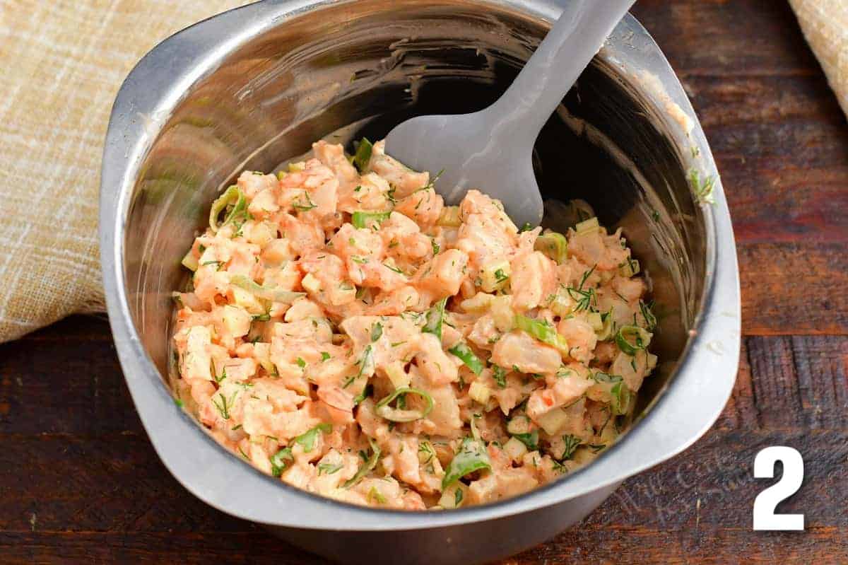 mixing shrimp salad in a silver mixing bowl and spatula.