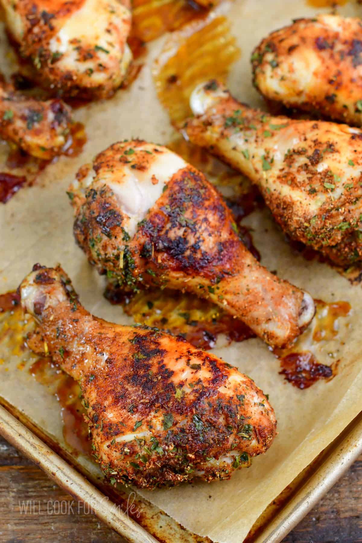 Baked drumsticks are presented on a parchment lined baking sheet.