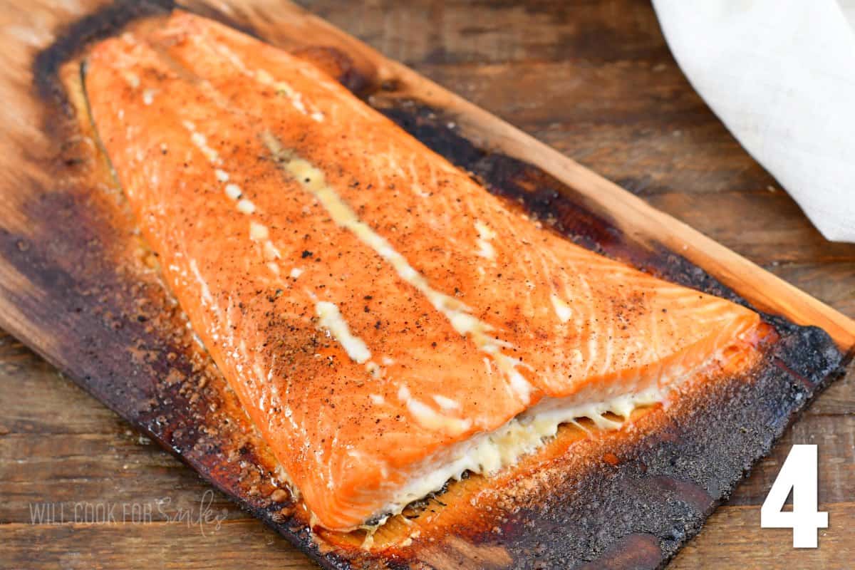 Cooked salmon is presented on a lightly charred wood plank.