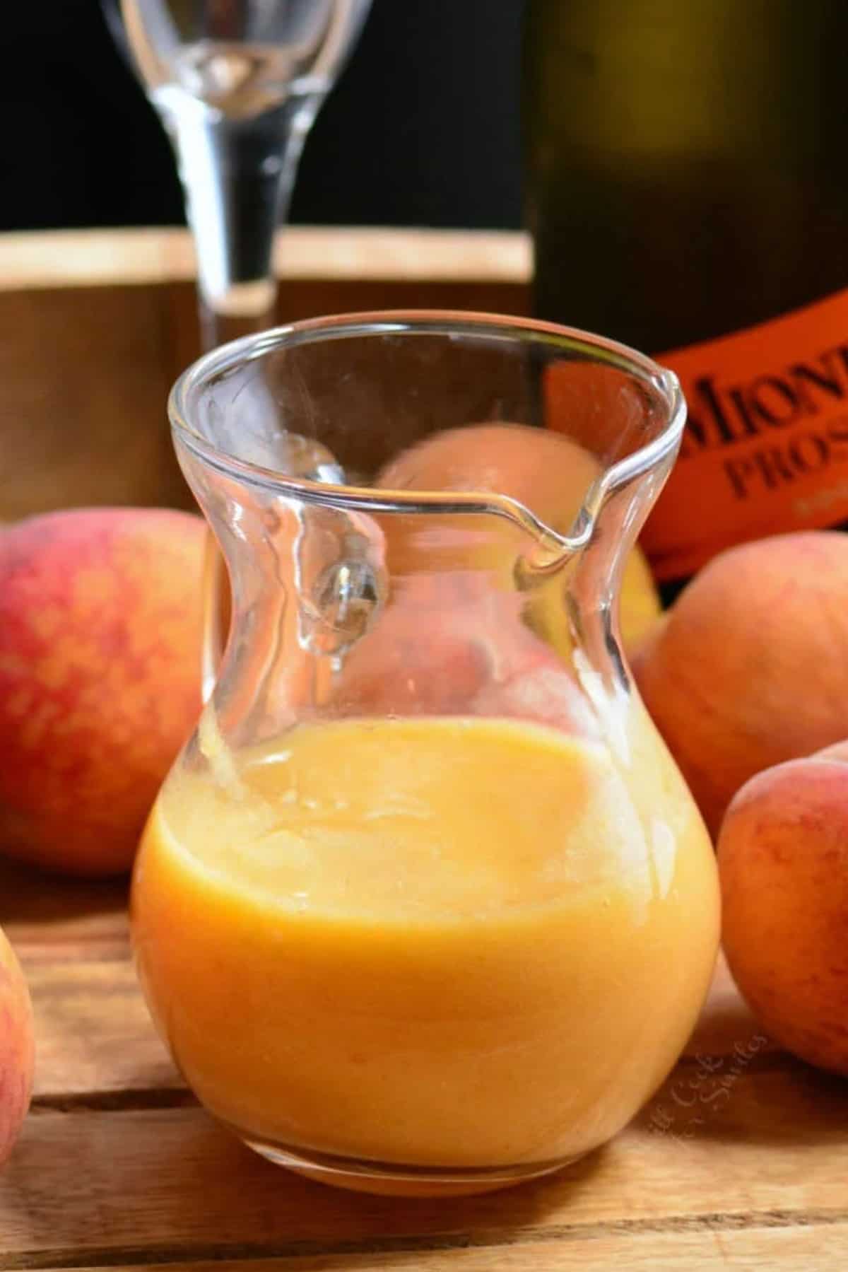A glass pitcher is halfway filled with peach puree.