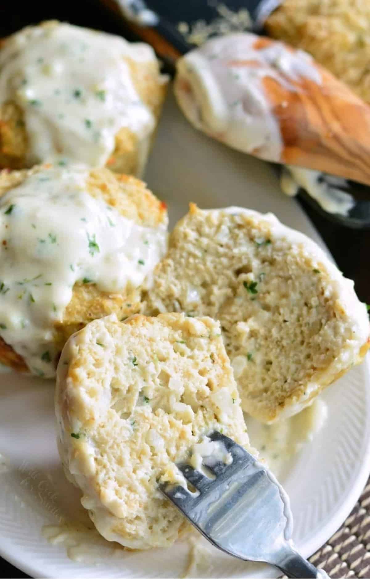 A fork is piercing a halved chicken meatloaf on a white plate.